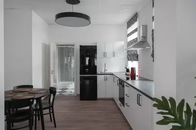 a kitchen with white cabinets and a table and chairs at Laurentroom Oldtown in Ukmergė