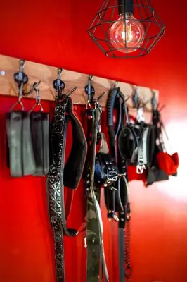 a group of equipment hanging on a red wall at BDSM Red Apartments in Vilnius