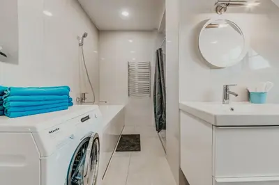 a white bathroom with a washing machine and a sink at Spacious - 140 square meters Apartment, Vilnius City Centre in Vilnius