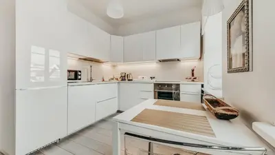a white kitchen with white cabinets and a table at Spacious - 140 square meters Apartment, Vilnius City Centre in Vilnius