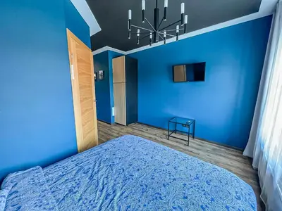 a blue bedroom with a bed and a chandelier at Apartments in Kaunas in Kaunas