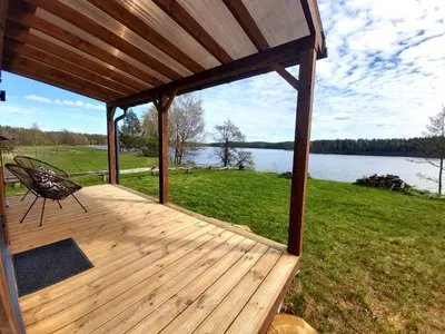 a wooden deck with a bench and a view of a lake at Siesarties Namukas in Mindūnai