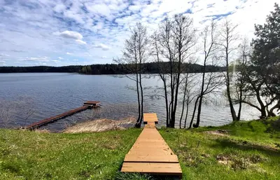 a wooden boardwalk leading to a lake with a bench at Siesarties Namukas in Mindūnai