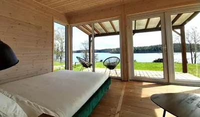 a bedroom with a bed and a view of a lake at Siesarties Namukas in Mindūnai
