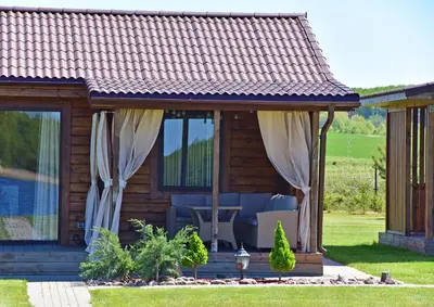 a log cabin with curtains and a patio at Vastapo Vilos in Kaniūkai