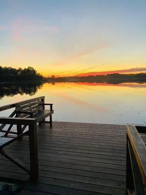 a wooden bench sitting on a dock next to a lake at Vastapo Vilos in Kaniūkai
