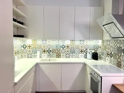 a kitchen with white cabinets and a tile wall at Vilnius Apartments & Suites – Old Town in Vilnius