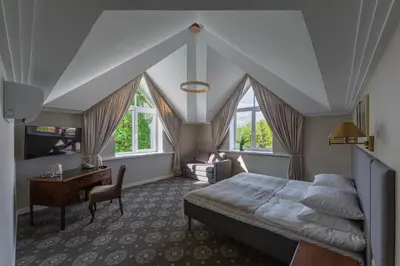 a bedroom with a bed and a desk and windows at Park Hotel Šiauliai SPA & Conference in Šiauliai