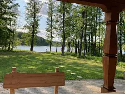 a wooden bench sitting under a gazebo overlooking a lake at Zarasaičio ežero sodyba in Magučiai