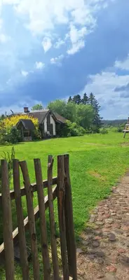 a wooden fence in a field with a house in the background at PO NENDRIŲ STOGU in Šiauliai