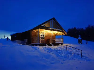 a log cabin in the snow at night at Namelis prie ežero in Miežoniai