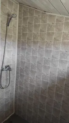 a shower in a bathroom with a tiled wall at Namelis prie ežero in Miežoniai