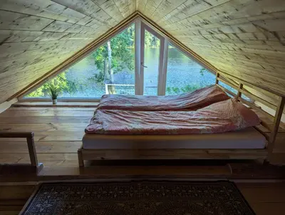 a bed in a room with a large window at Namelis prie ežero in Miežoniai