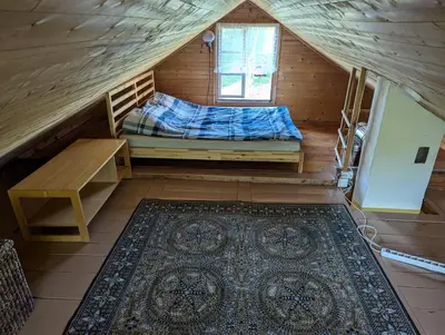a small attic room with a bed and a rug at Namelis prie ežero in Miežoniai