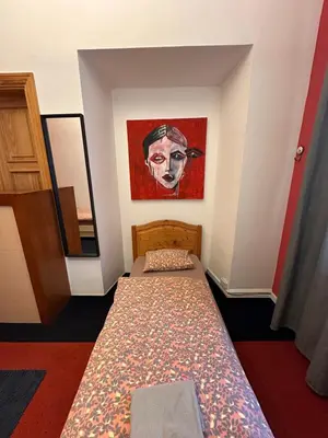 a bedroom with a bed with a painting on the wall at 25 Hours Hostel in Vilnius