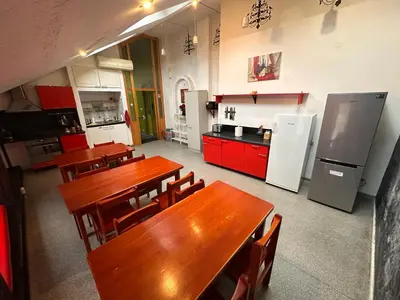 a large kitchen with wooden tables and red cabinets at 25 Hours Hostel in Vilnius
