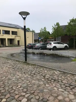 a street light with cars parked in a parking lot at Daukanto apartamentai in Anykščiai