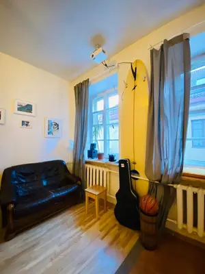 a living room with a black leather couch and a surfboard at Jimmy Jumps House in Vilnius