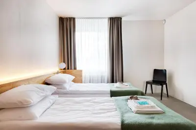 a hotel room with two beds and a chair at Tech Spa Coliving&Coworking Spaces in Druskininkai