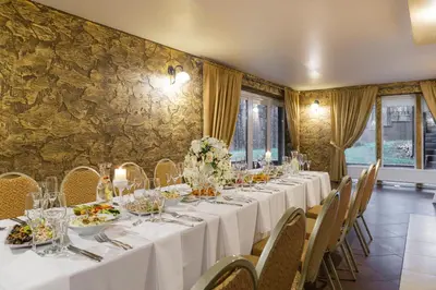a long dining room with white tables and chairs at Vila Kelmyne in Molėtai