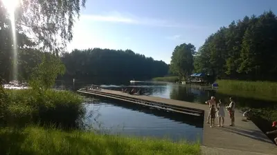 a group of people standing on a dock next to a river at Vila Kelmyne in Molėtai
