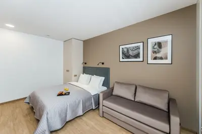 a bedroom with a bed and a chair at River city apartments in Kaunas