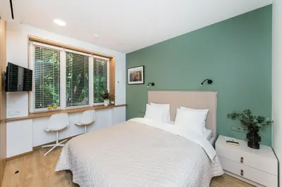 a bedroom with a bed and two chairs and a window at River city apartments in Kaunas