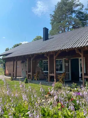 a log cabin with a garden and flowers at Palūšės Kempingas (kambariai) in Palūšė