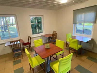 a dining room with yellow chairs and tables and windows at Palūšės Kempingas (kambariai) in Palūšė
