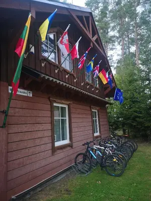 a group of bikes parked outside of a building with flags at Palūšės Kempingas (kambariai) in Palūšė