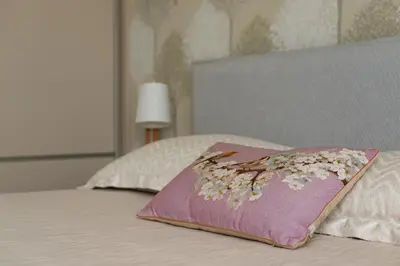 a pink pillow with flowers on top of a bed at 39DO in Druskininkai