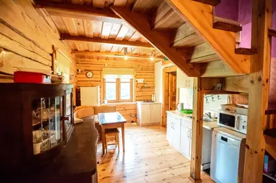 a kitchen with wooden floors and a table in a cabin at Pas Kaziuką namas-sodyba in Ignalina
