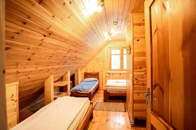 a room with two beds in a wooden cabin at Pas Kaziuką namas-sodyba in Ignalina