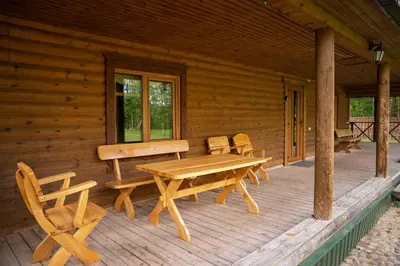a porch of a log cabin with a picnic table and chairs at Pas Kaziuką namas-sodyba in Ignalina