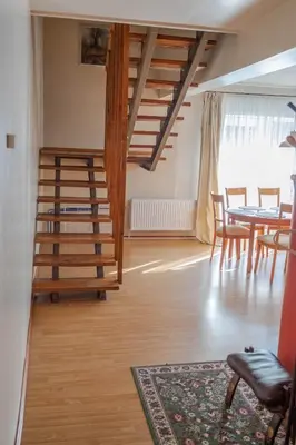 a living room with a wooden staircase and a table at Apartamentai Šilas in Druskininkai