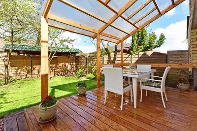 a patio with a table and chairs on a wooden deck at Apartamentai Šilas in Druskininkai