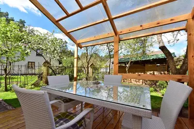 a patio with a glass table and chairs on a deck at Apartamentai Šilas in Druskininkai