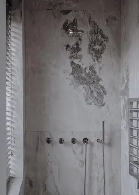 a bathroom with a shower with a marble wall at Bōheme House in Kaunas