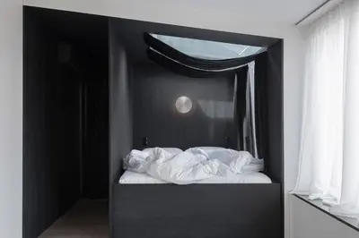 a bedroom with a bed with white sheets and a window at Bōheme House in Kaunas