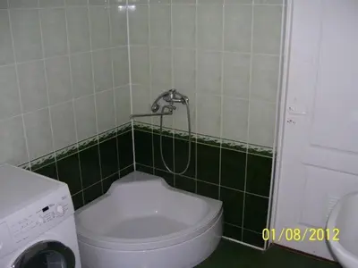 a bathroom with a toilet in a green tiled wall at Pirtis Prie Neries Jonava in Jonava