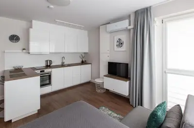 a kitchen and living room with white cabinets at Studio Ligita near Egle in Druskininkai