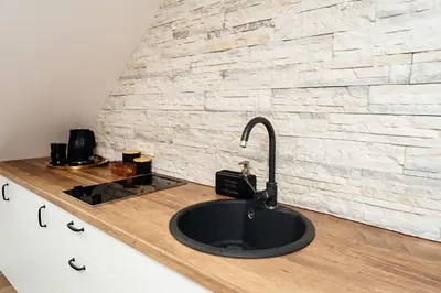 a kitchen counter with a sink and a brick wall at Domus Fortuna in Vilnius