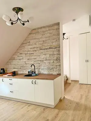 a kitchen with white cabinets and a brick wall at Domus Fortuna in Vilnius