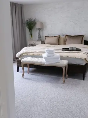 a bedroom with a large bed with a bench and towels on it at Naktakės apartamentai in Kupiškis