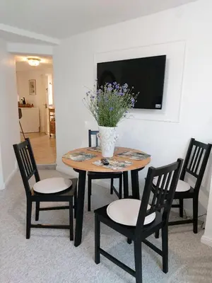 a table with chairs and a vase with flowers on it at Naktakės apartamentai in Kupiškis
