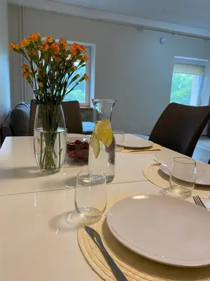 a table with plates and glasses and flowers in a vase at V15 Apartment in Druskininkai