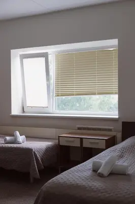 a bedroom with two beds and a window with blinds at Motelis Gariūnai in Vilnius