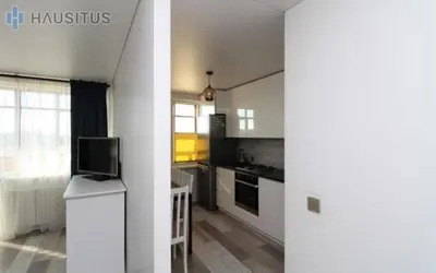 a kitchen with white cabinets and a tv on a counter at Nemuno apartamentai in Panevėžys