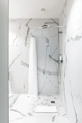 a bathroom with white marble walls and a shower at Place No. 2 in Vilnius