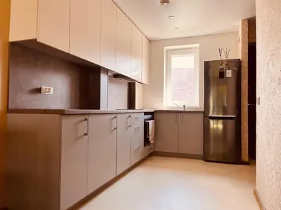 a kitchen with white cabinets and a stainless steel refrigerator at Comfortable Townhouse in Vilnius